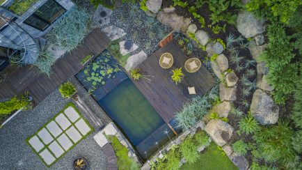 Petite piscine naturelle écologique vue d'en haut, avec terrasse de bois, plantations et rochers.
