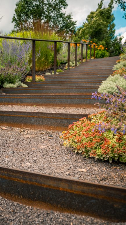 Escalier d'acier bordé de plantations dans un aménagement paysager