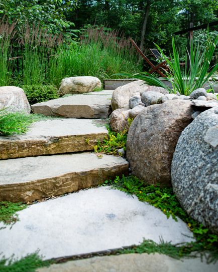 Escalier de pierre naturelle bordé par de gros rocher de granit et des insertions de couvres-sols